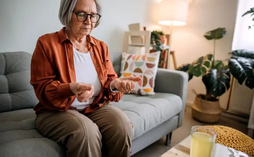 Cannabis gegen Arthrose: Seniorin blickt auf ihre Hände.